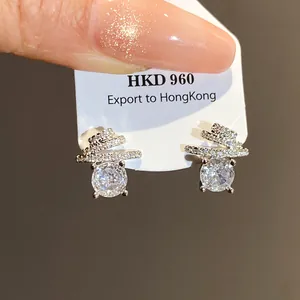 Macro detail showing round zircon stud earrings with a silver-toned spiral pavé design
