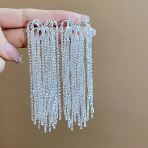 Detail view of silver firework-style glass beaded fringe earrings held by a hand.