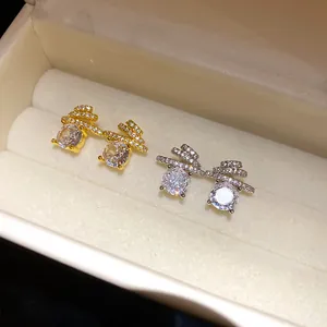 Close-up detail of gold and silver stud earrings with large round cubic zirconia stones