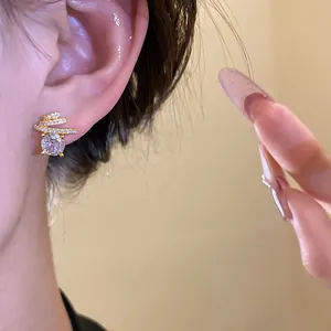 Detailed macro view of an exquisite gold-plated zircon round stud earring worn on a female ear