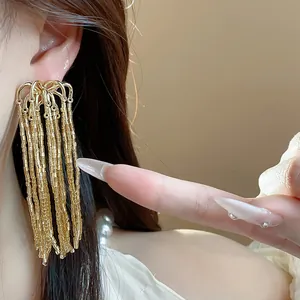 Detailed view of elegant gold tassel earrings featuring a firework glass design on model.