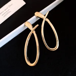 Close-up of elegant gold-plated hollow cross earrings with a polished mirror finish