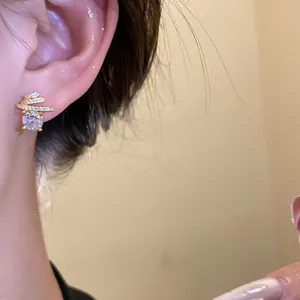 Exquisite golden stud earrings with round zircon and spiral pavé stones close-up view