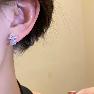 Close-up view of elegant silver zircon stud earring worn on an ear with a sparkling large stone.
