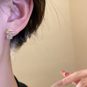 Macro detail view of a gold-plated spiral stud earring featuring a sparkling round zircon stone.