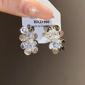 Close-up detail of silver flower stud earrings featuring shimmering white zircon stones