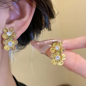 Detailed view of vintage gold-plated flower stud earrings with sparkling zircon centers.