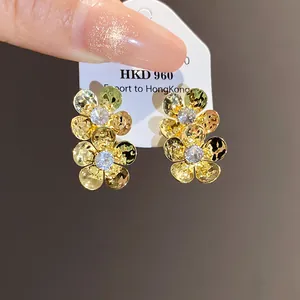 Close-up of vintage golden flower stud earrings with sparkling zircons on a card