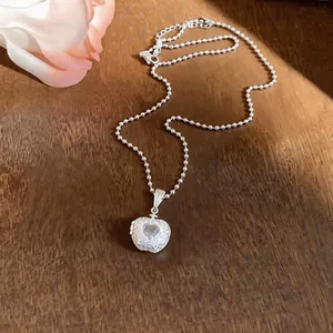 Dettaglio di una collana con ciondolo a mela in zircone argento su legno