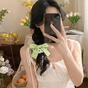 Elegantes grünes Haargummi mit Schleife und Punkten auf einem Model im Spiegel-Selfie