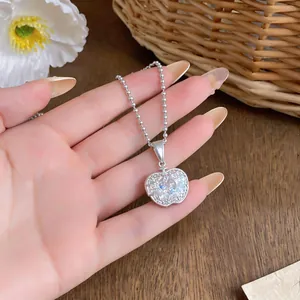 Primo piano di una collana con ciondolo a forma di mela e pietre di zircone a cuore