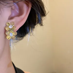 Detailed view of vintage gold zircon flower stud earrings showing hammered texture