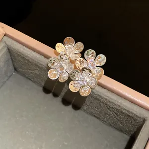 Close-up of sparkling zircon flower ear studs with golden finish and hammered petals