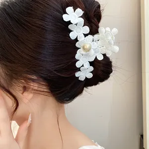Elegant close-up view of a white fabric flower hair claw clip with a pearl accent on a bun