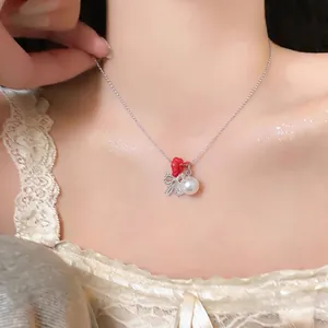 Elegant minimalist silver chain necklace with red bow and pearl charms on a model