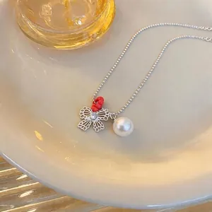 Elegant silver-toned necklace with filigree butterfly pendant and white pearl charm