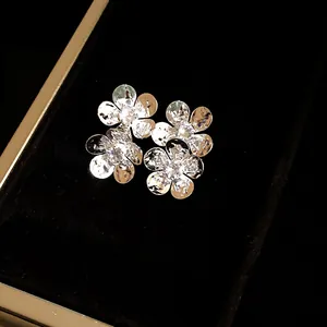Detailed close-up of vintage silver flower stud earrings with sparkling zircon centers