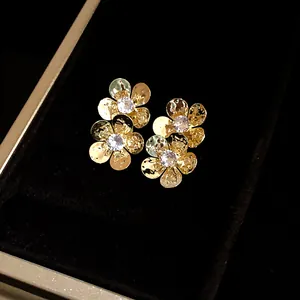 Close-up of vintage flower stud earrings with zircon centers in a luxury gold finish