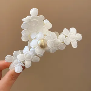 Detailed view of an elegant white fabric flower hair claw clip with a central pearl decoration