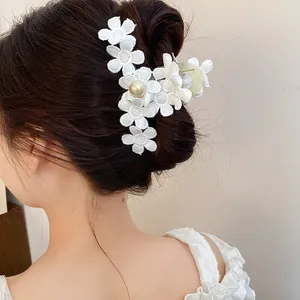 Detailed close-up of white fabric flower hair claw clip with pearl accent on hair