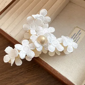 Detail view of the delicate white lace flower hair claw clip with a glossy pearl center