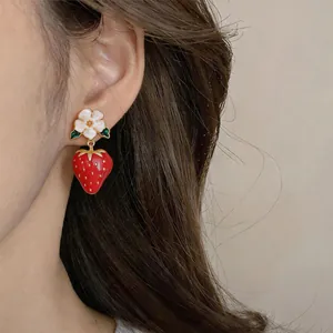 Detailed close-up view of sweet strawberry and white flower drop earrings worn on ear