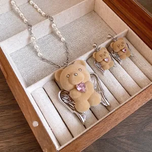 Cute flocked teddy bear pendant necklace with pearls and wings in a wooden jewelry box.