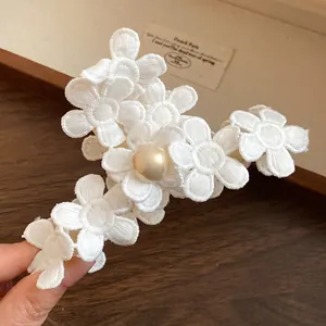 Detailed macro view of white lace fabric flower hair claw clip featuring elegant pearl