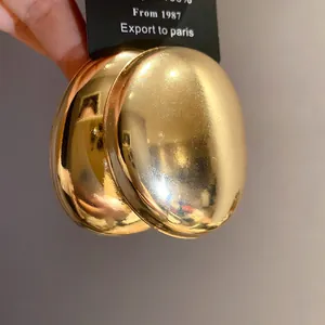 Macro detail of shiny gold metallic oval stud earrings on a black jewelry card