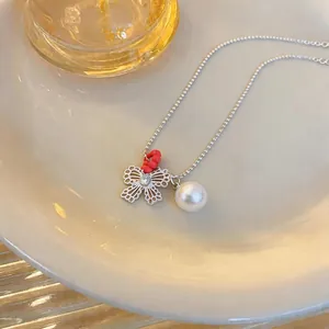 Close-up detail of silver hollow bow necklace featuring a white pearl and zircon