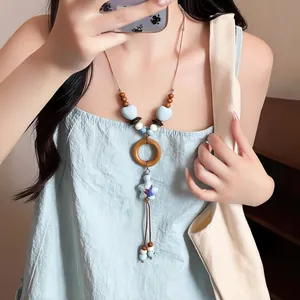 Detail of long Bohemian shell necklace with star pendant worn by model on vacation.