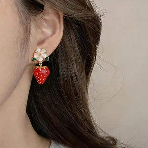 Detailed close-up showing cute strawberry and white flower drop earrings on a model