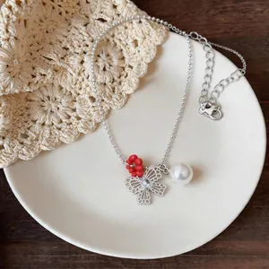 Close-up of silver ball chain necklace with hollow butterfly pendant and pearl detail.