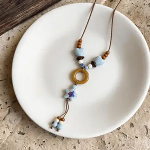 Close-up of bohemian necklace with blue star and heart beads on white plate
