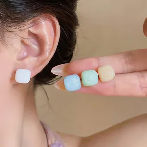 Primer plano de pendientes cuadrados de resina Morandi con textura de purpurina muy fina.