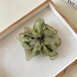 Nahaufnahme eines eleganten grünen Organza-Haargummis im Waldstil