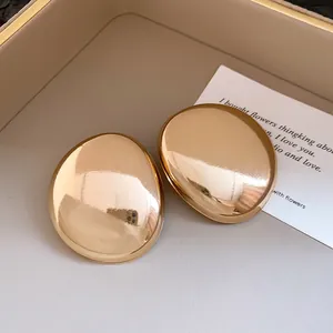 Macro view of high-quality oversized glossy gold oval stud earrings with smooth finish