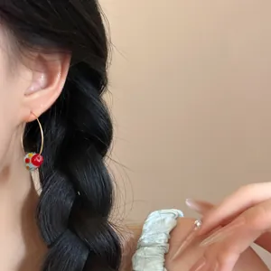 Detailed view of fashionable summer style hoop earring with colorful beaded pendant worn by model