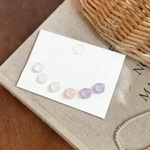 Primer plano detallado de pendientes cuadrados de resina en colores Morandi suaves