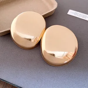 Detailed macro shot showing the smooth texture of glossy gold oval stud earrings.