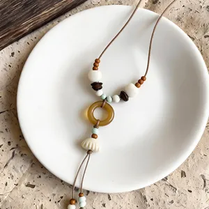 Detailed close-up of Bohemian shell necklace with amber ring and assorted beads