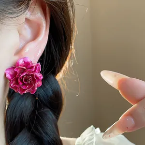 Macro detail of a fuchsia resin rose stud earring worn on ear with braided hair