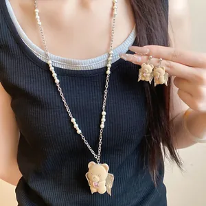 Model wearing a sweet flocked bear pendant necklace with matching pearl chain and earrings