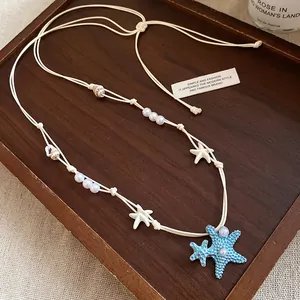 Dettaglio della collana mare con stella marina blu e ciondoli in conchiglia naturale.