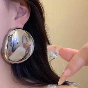 Close-up of large silver oval metallic stud earring with a shiny mirror finish effect.