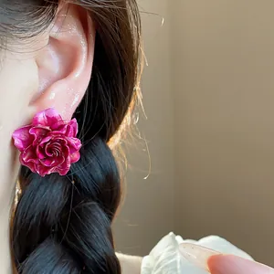 Close-up macro view of a stylish fuchsia resin rose flower stud earring worn on ear
