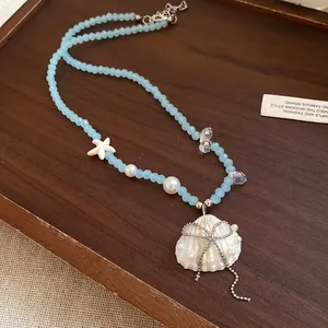 Primo piano della collana di conchiglie con perline azzurre, stella marina e fiocco.