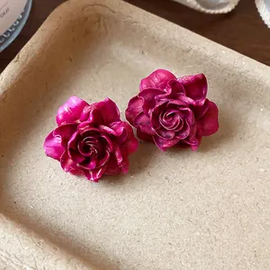 Detailed macro view of elegant magenta resin rose stud earrings with silver needles.