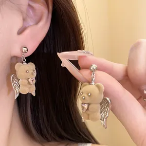 Detail of cute flocked bear earrings with silver angel wings and pink heart