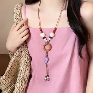 Bohemian shell necklace with wooden beads and purple pendant on pink dress model